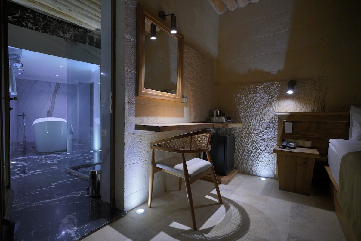 A modern bathroom with a glass shower enclosure, a wooden chair, and a mirror above a sink.