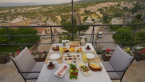 A table set for breakfast with a scenic view of a mountainous landscape. - Kappadoks Cave Hotel (Nevsehir)