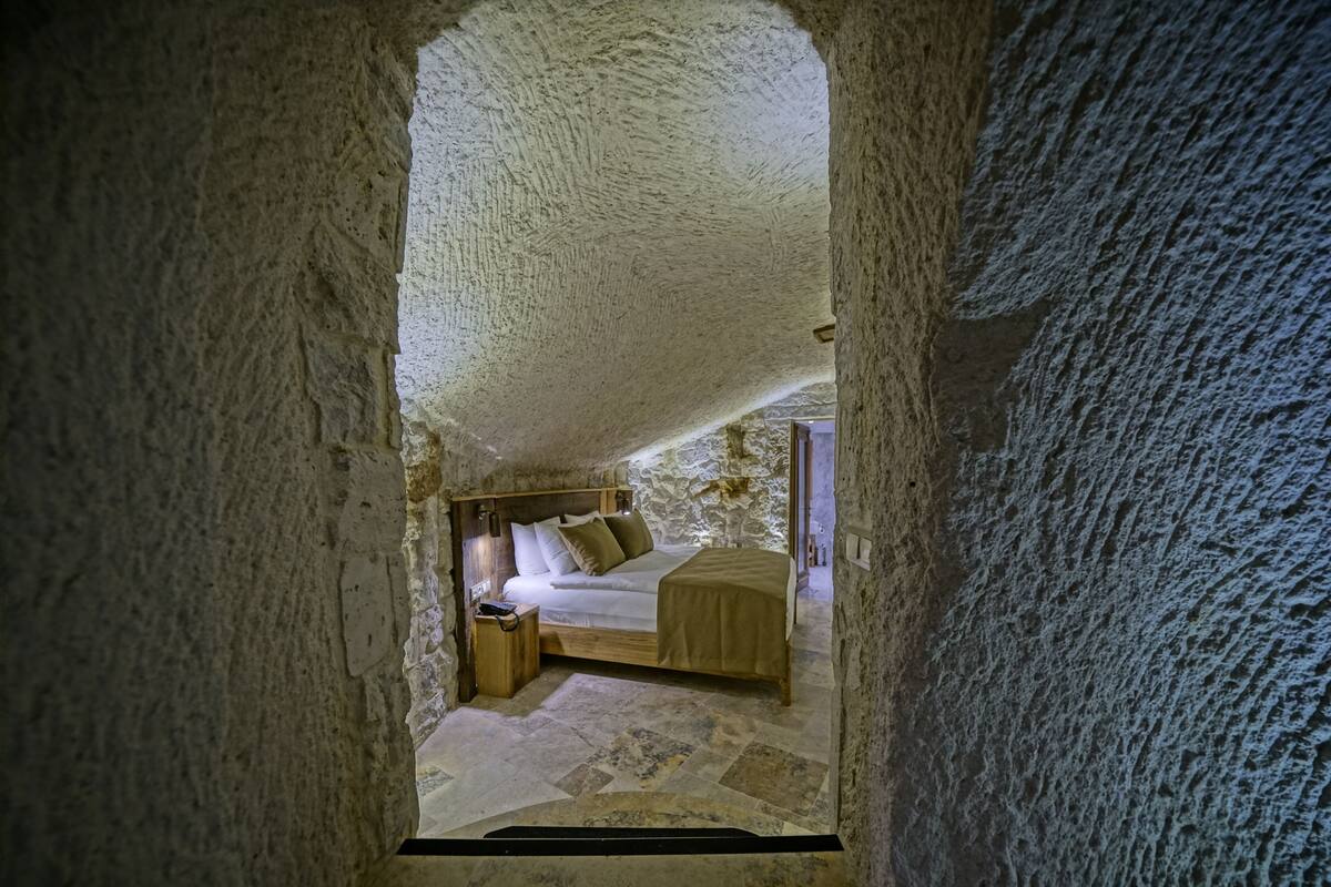 A bedroom with a stone ceiling, a wooden bed, and a nightstand.