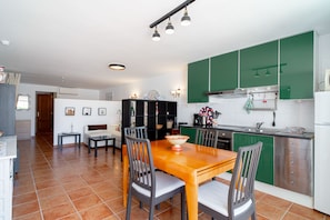 A modern kitchen with green cabinets, a dining table with chairs, and a visible kitchen island.