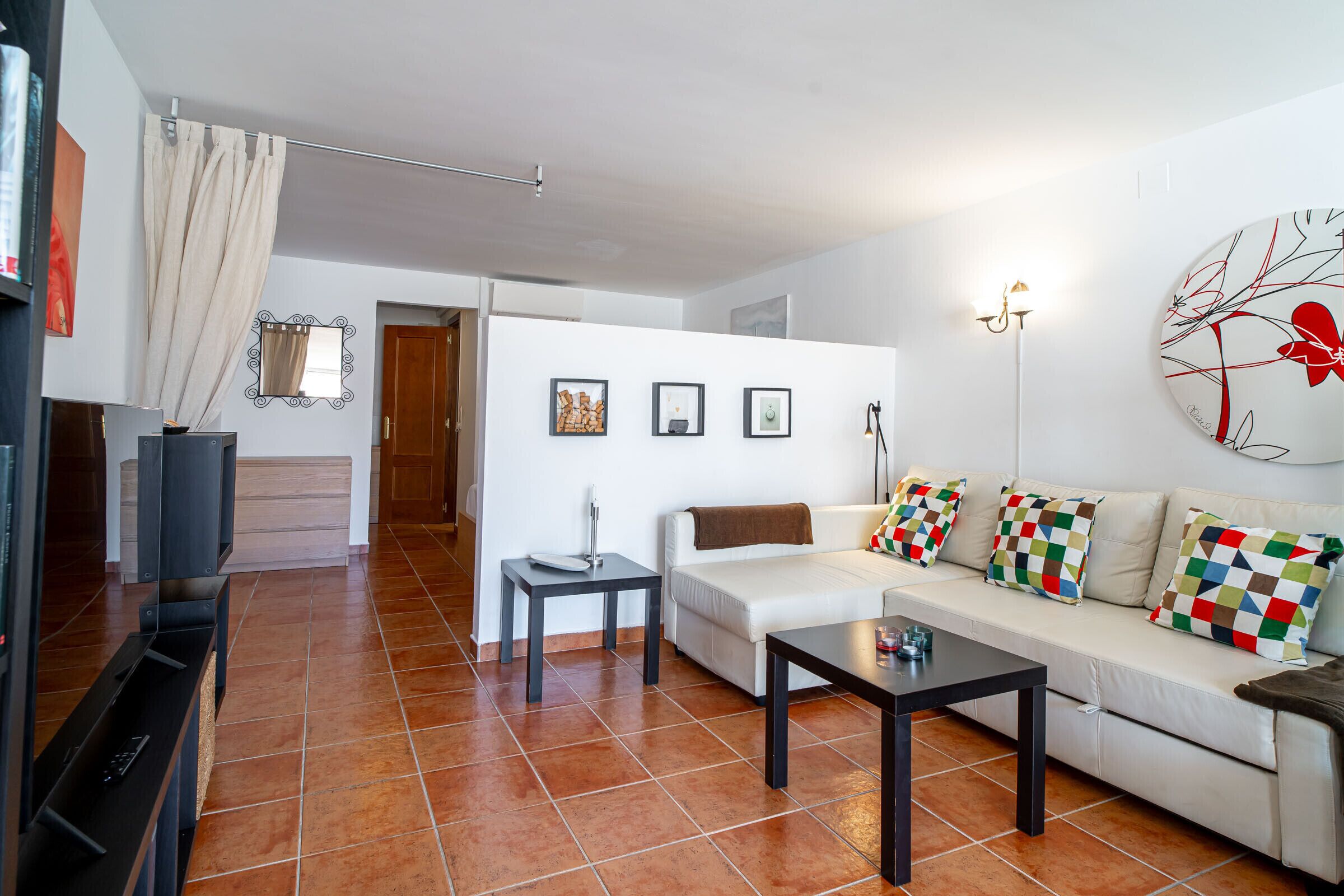 Una sala de estar con un sofá, una mesa de centro, un televisor y una lámpara.