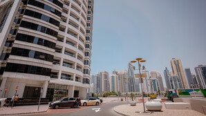 A modern urban street with high-rise buildings, a roundabout, and a parked car. - ZAPBED House - AWP 1501 (Dubai)