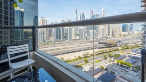 A balcony with a city view, a white chair, and a table. - ZAPBED House - AWP 1501 (Dubai)