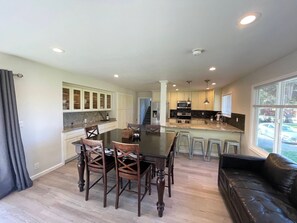 A modern kitchen with a dining area, a bar, and a view of the outside.