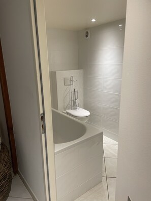 Ein modernes Badezimmer mit Badewanne, Toilette und Duschbereich.