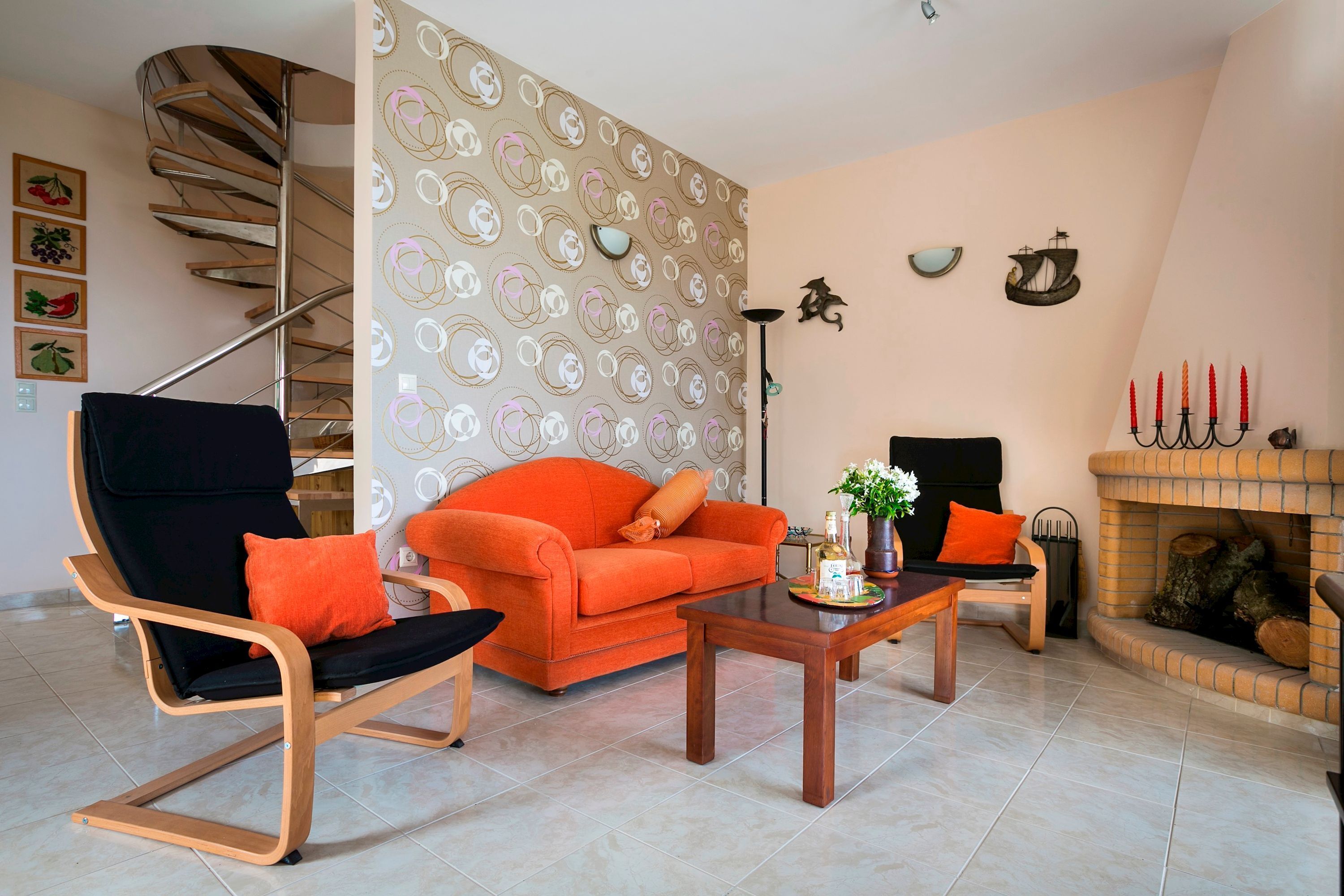 Ein Wohnzimmer mit Wendeltreppe, Sofa, Sessel, Couchtisch und Kamin.