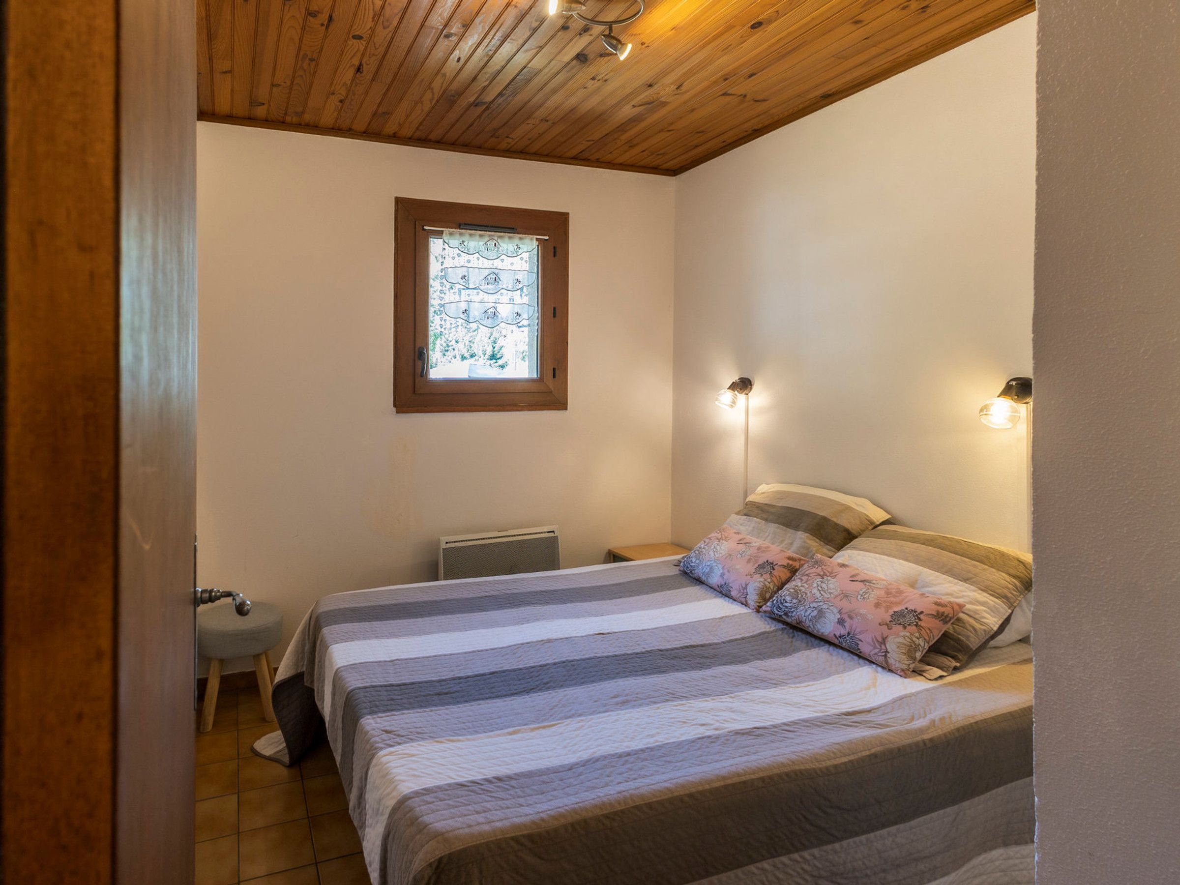 A bedroom with a bed, a window, a radiator, and a bedside lamp.