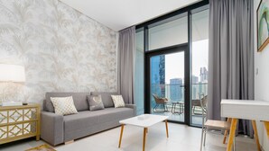 A modern living room with a grey sofa, white coffee table, and a city view through large windows. - GLOBALSTAY. New Marquise Square Building in Business Bay (Dubai)