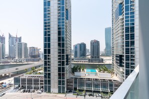 Un edifici alt amb façana de vidre moderna, una piscina al terrat i vistes a l'horitzó urbà circumdant.