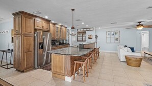 A spacious kitchen with wooden cabinets, a large island, and bar stools. - Gulf Access, Minutes to the River, Kayaks & Dog Friendly - Aqua Escape - Roelens Vacations (Cape Coral)