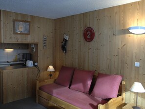 A small wooden room with a bed, a kitchenette, and a wall-mounted sign. - South-facing studio cabin, 4 pers, balcony, ski locker (Valloire)