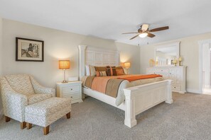 A bedroom with a bed, nightstands, a chair, a ceiling fan, and a dresser.