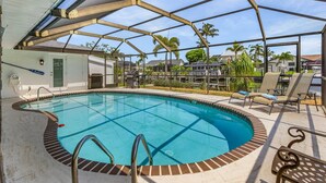 An indoor swimming pool with a clear view of the surrounding area, including a covered patio and lounge chairs. - Boat lift -Direct Gulf Access, Great Spaces inside & out!  - Villa Ocean Pearl - Roelens Vacations (Cape Coral)