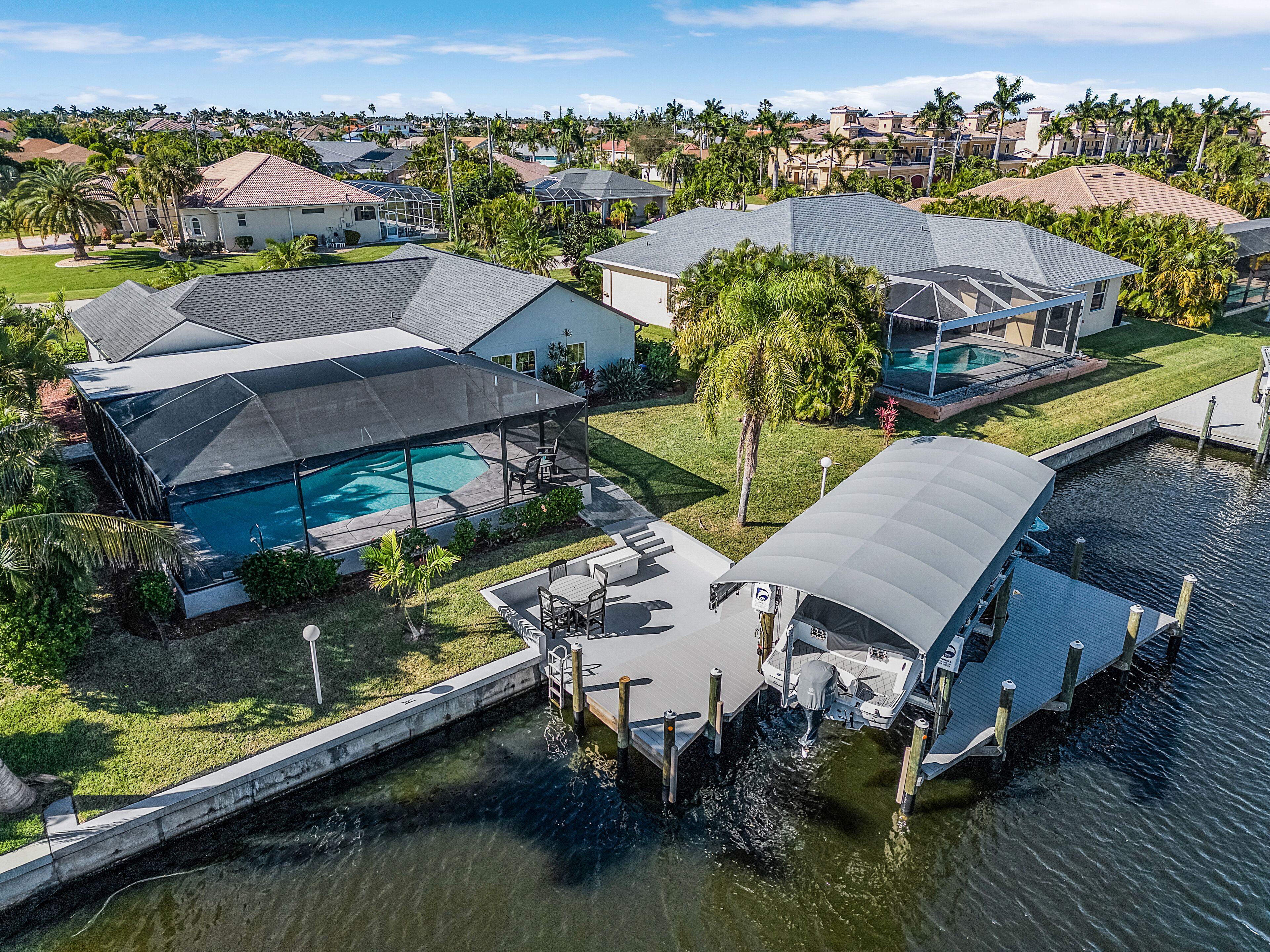 A residential area with houses, a swimming pool, and a dock extending into a body of water.