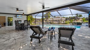 Ein Poolbereich im Innenbereich mit Liegestühlen, einem Tisch und Deckenventilatoren.