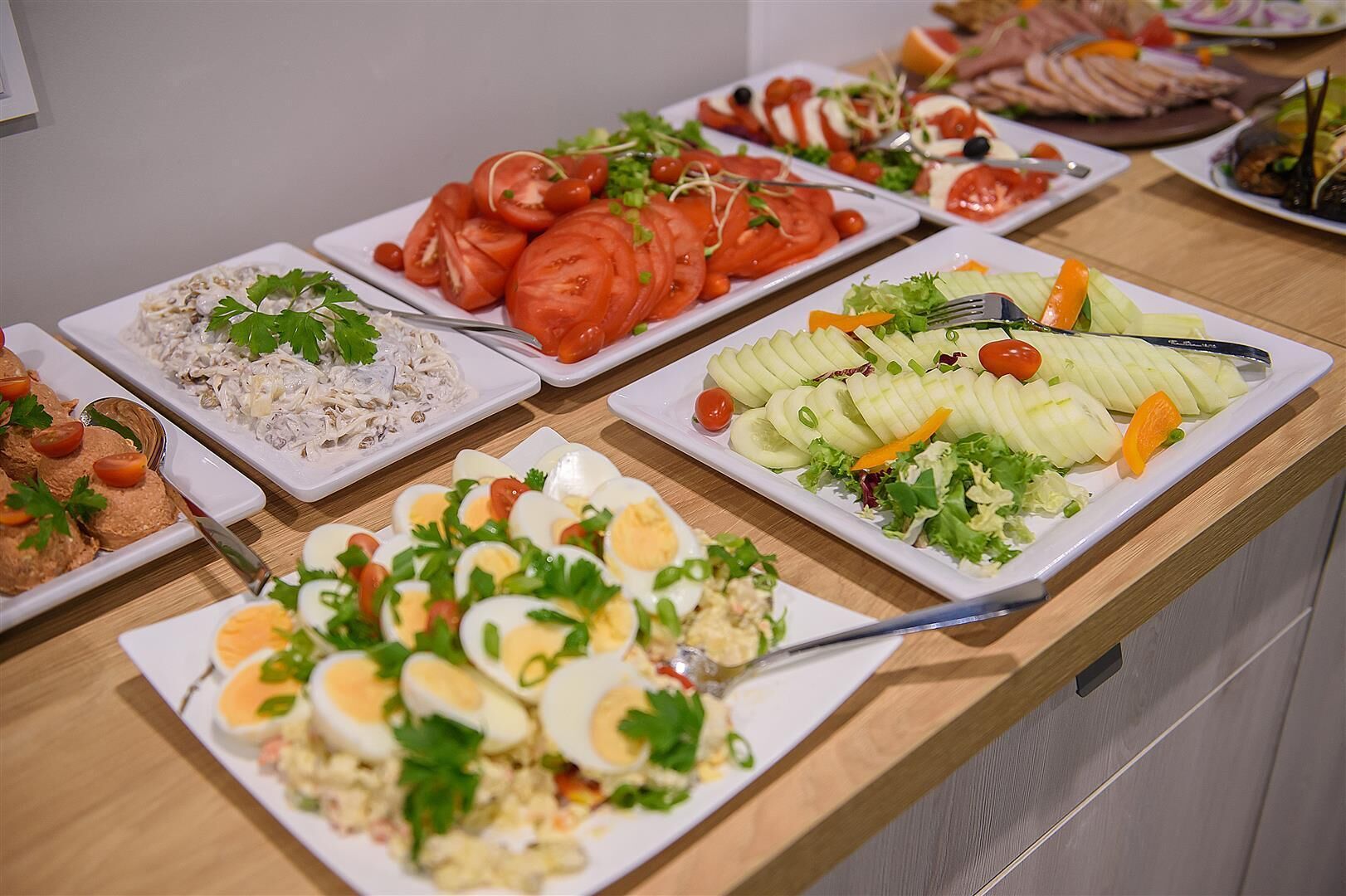 A buffet table with various dishes including sliced tomatoes, cucumbers, and eggs.