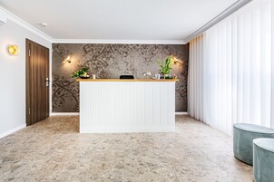 Una zona de recepción con un mostrador de madera, dos luces fijadas a la pared y un papel tapiz decorativo.