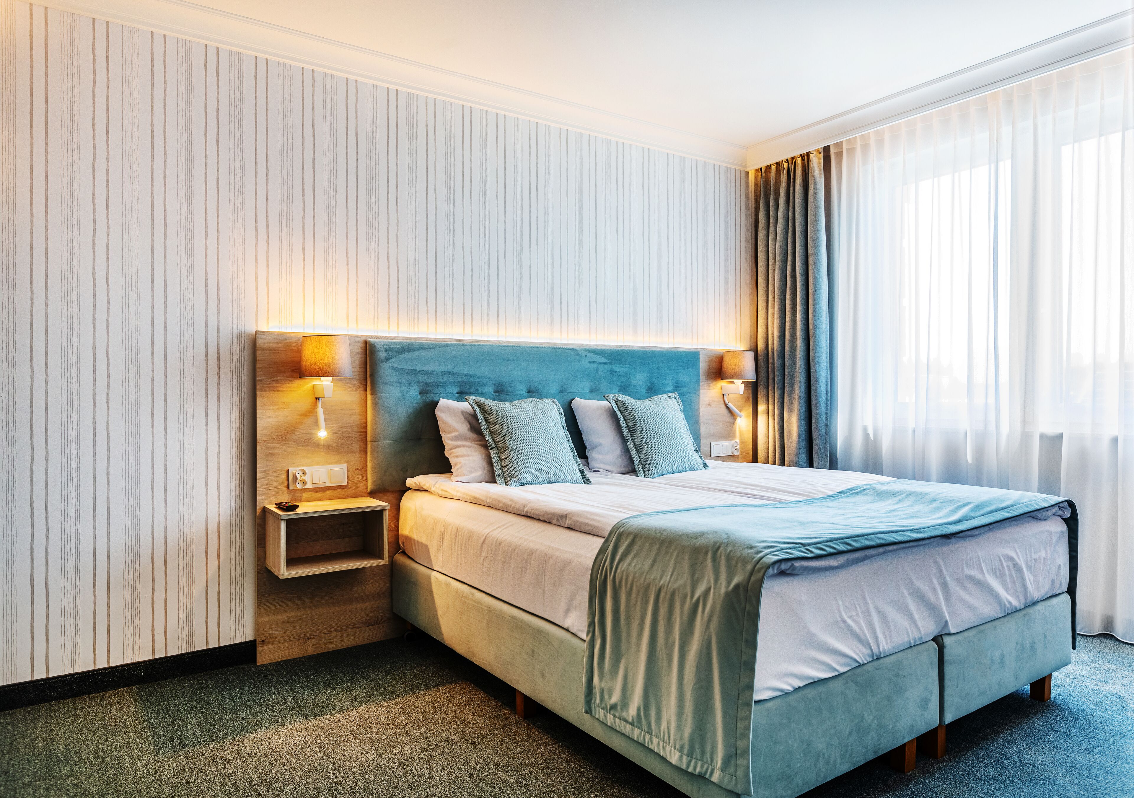 Quarto de hotel com cama, mesas de cabeceira e vista para o exterior.