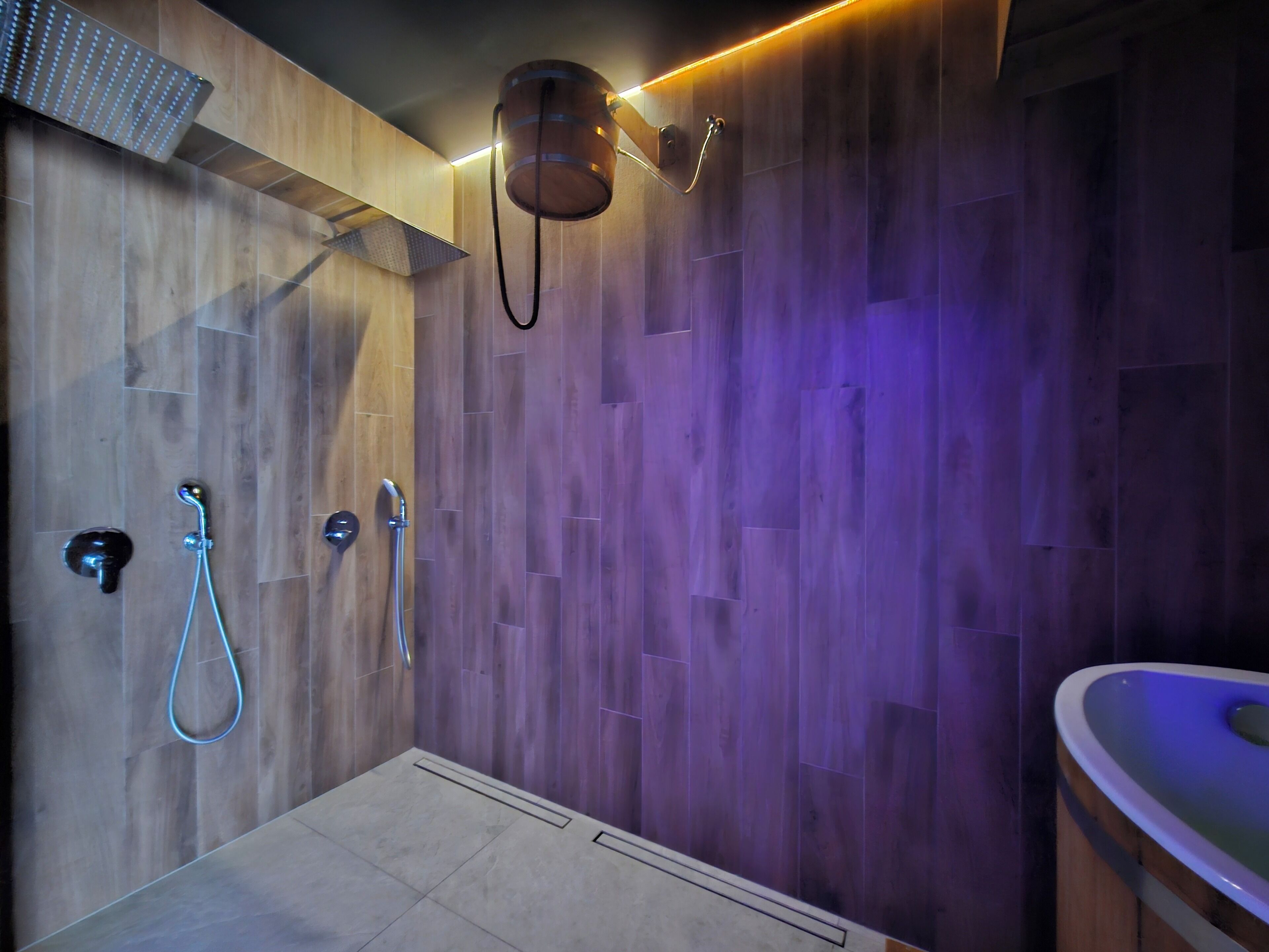 Un baño moderno con paneles de madera, ducha con cabezal de ducha manual y bañera con asiento integrado.