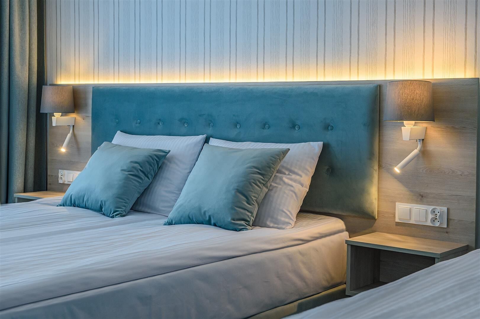 A modern bedroom with a tufted headboard, two bedside lamps, and a neutral color scheme.