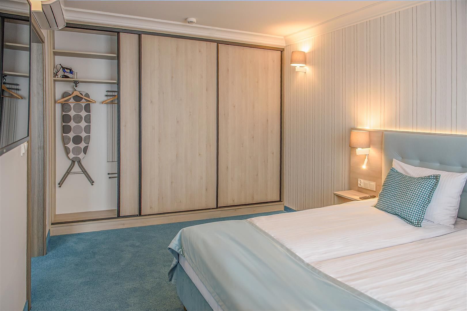 A bedroom with a bed, a wardrobe, and a hanging rack with clothes.