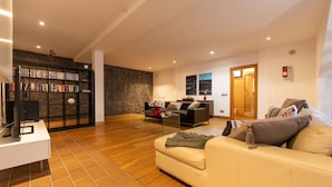 A spacious living room with a large bookshelf, a sofa, and a coffee table. - Villa in Marina Rubicon with Pool (Playa Blanca)