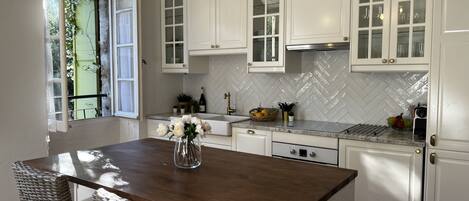 A kitchen with white cabinets, a herringbone tile backsplash, and a wooden island with chairs.