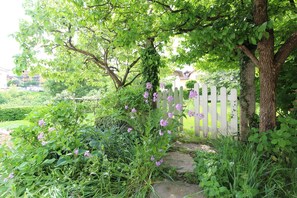 A garden with a white picket fence, lush greenery, and flowering plants.