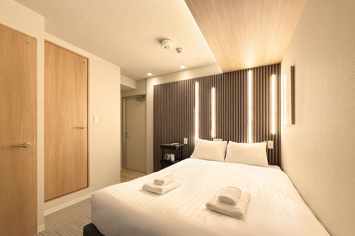 A hotel room with a large bed, wooden wardrobe, and a modern design.