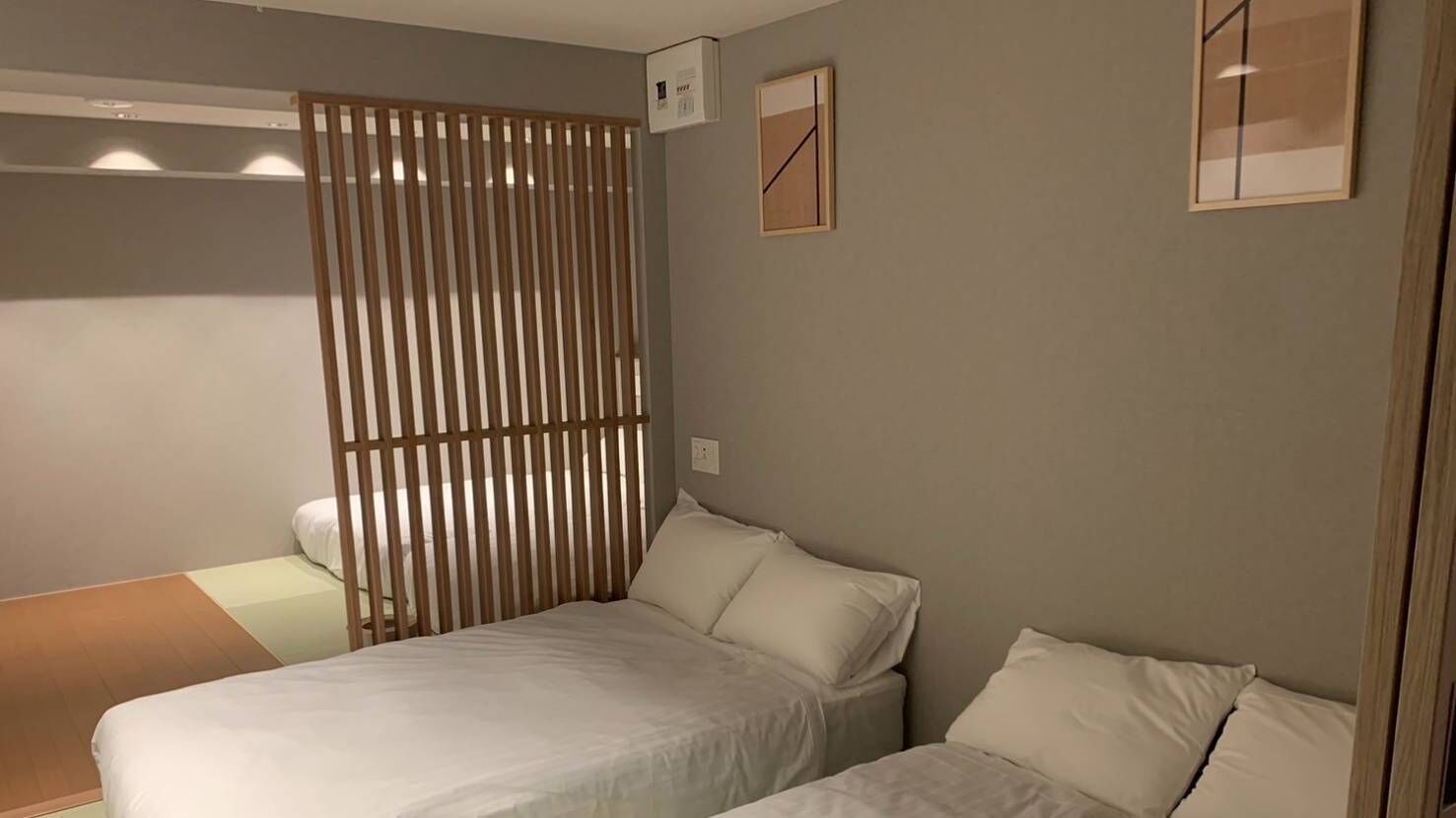 A bedroom with a bed, a wooden partition, and a small bedside table.