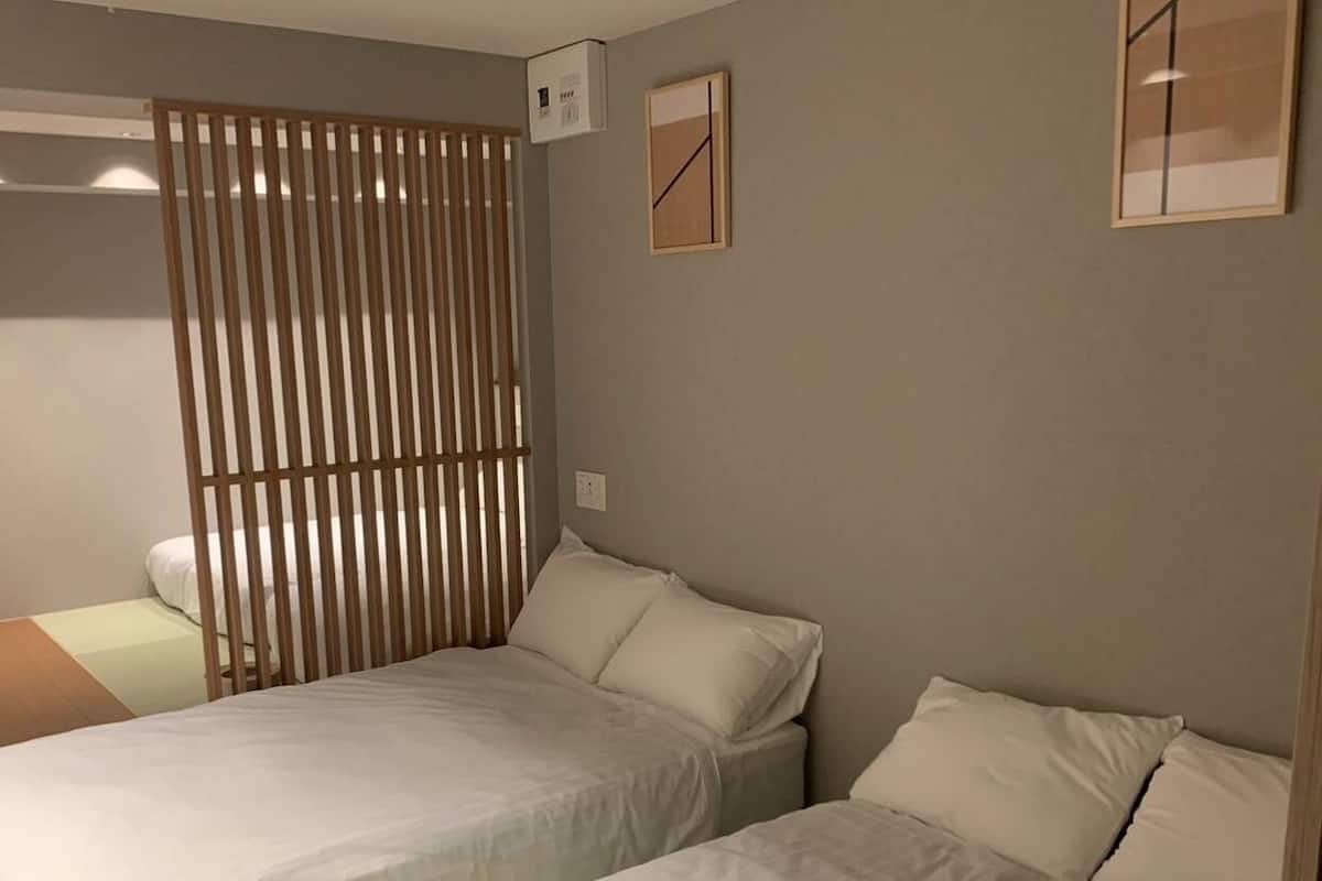 A bedroom with a bed, a wooden partition, and a small bedside table.