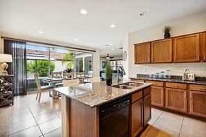 A modern kitchen with granite countertops, wooden cabinets, and a built-in dishwasher. - Beautifully Furnished Home in Power Ranch ~ Steps away from Community Pool & Spa (Gilbert)