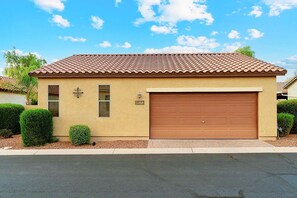 A two-story house with a brown tiled roof, a garage, and a small front yard with trimmed bushes. - Beautifully Furnished Home in Power Ranch ~ Steps away from Community Pool & Spa (Gilbert)