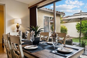 A dining area with a table set for two, featuring a checkered tablecloth, two chairs, a lamp, and potted plants. - Beautifully Furnished Home in Power Ranch ~ Steps away from Community Pool & Spa (Gilbert)