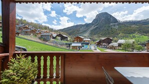 Un balcon en bois offrant une vue sur une montagne et une station de ski.