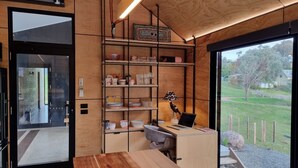 A modern interior with a wooden desk, shelves with kitchenware, and a laptop.