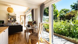 Un salon moderne avec un coin repas, de grandes fenêtres et une vue sur un jardin luxuriant.