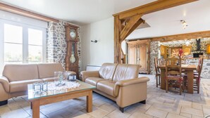 Amplia sala de estar con pared de piedra, una mesa de comedor de madera con sillas, un sofá de cuero y una mesa de centro de vidrio.