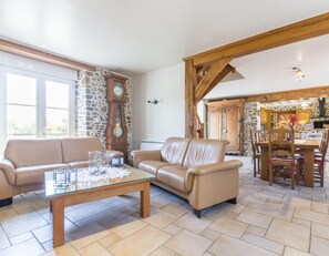 Un vaste espace de vie agrémenté d’un mur en pierre, d’une table à manger en bois avec des chaises, d’un canapé en cuir et d’une table basse en verre.