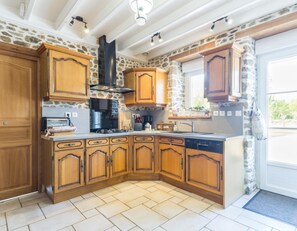 Une cuisine avec des meubles de rangement en bois, une cuisinière à gaz et une hotte aspirante noire.