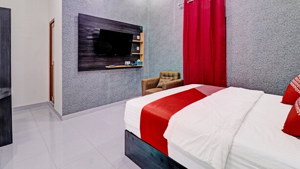 Un dormitorio moderno con una cama grande, un televisor de pantalla plana montado en la pared y una cortina roja.