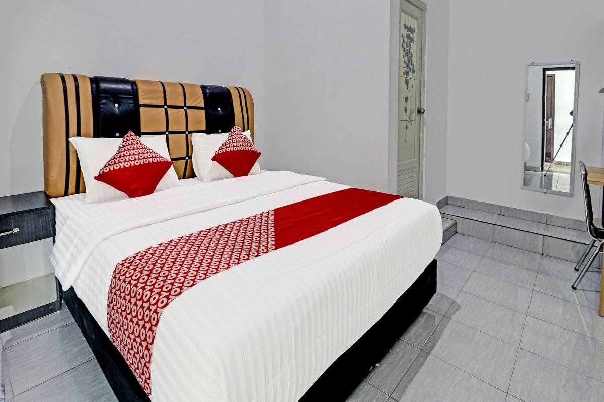 Una cama bien hecha con una colcha estampada y almohadas, un cabecero moderno y un piso limpio con baldosas.