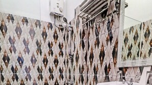 Un baño con pared de azulejos estampados, inodoro, lavamanos y zona de ducha.