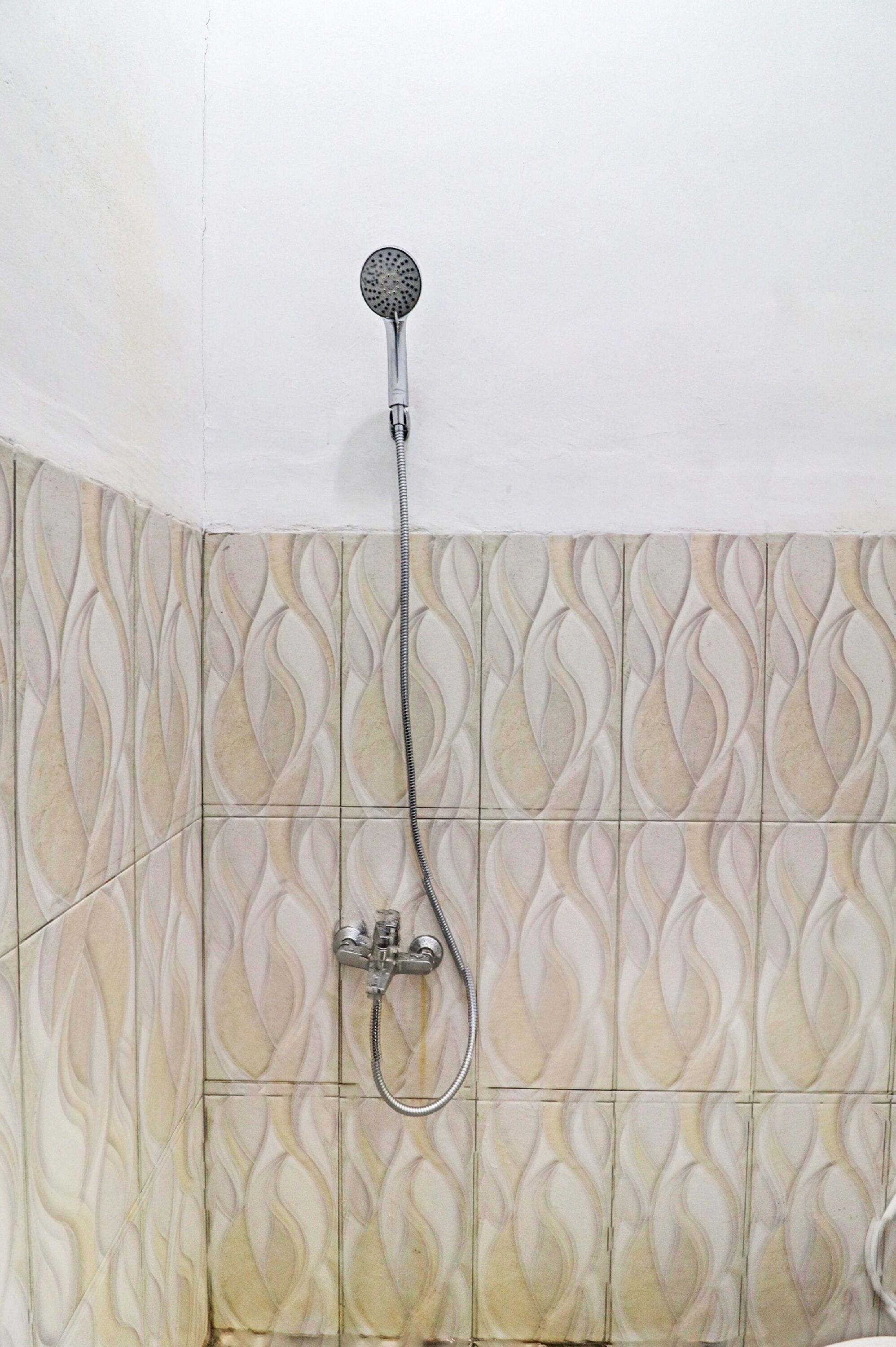 A shower with a handheld showerhead and a wall-mounted control valve.