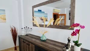 A wooden console table with a mirror, decorative items, and a vase with dried pampas grass.