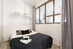 A hotel room with a bed, a window, and a shelf above the bed. - Bronze-2525-Lovely renovated apartment (Cannes)