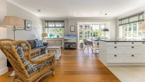 Ein geräumiges Wohnzimmer mit einer Couch, einem Korbstuhl und einem Essbereich mit Kücheninsel.