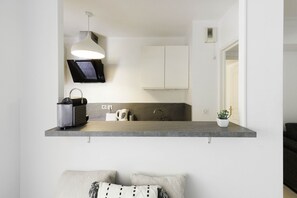 A modern kitchen with a built-in microwave, kettle, and coffee maker on a grey countertop.