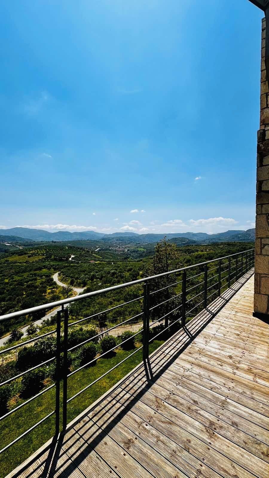 A wooden deck with a metal railing overlooking a mountainous landscape.