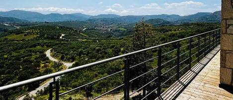 A wooden deck with a metal railing overlooking a mountainous landscape.